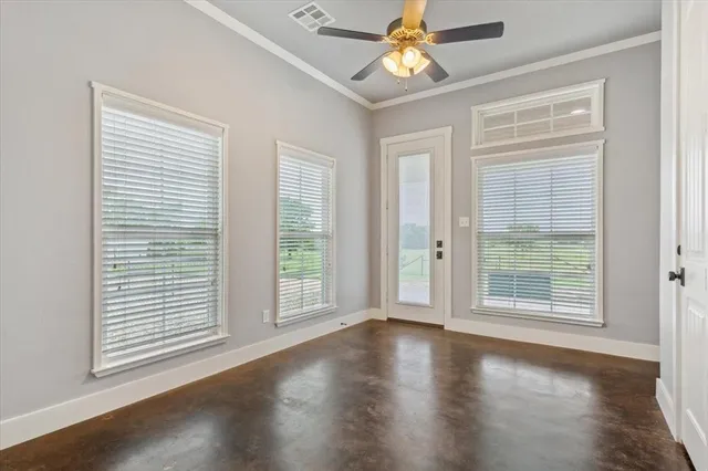 an empty room with wooden floor chandelier fan and windows