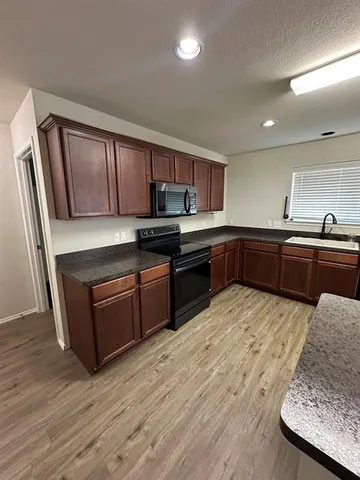 a kitchen with stainless steel appliances granite countertop a stove top oven a sink dishwasher and wooden cabinets