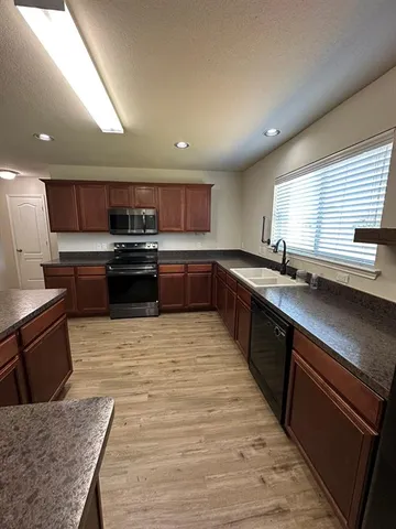 a large kitchen with stainless steel appliances granite countertop a sink stove and refrigerator