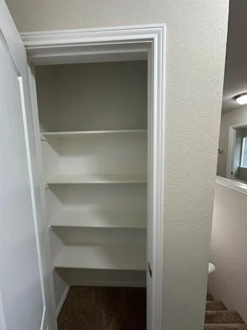 en empty room with closet and a chandelier fan