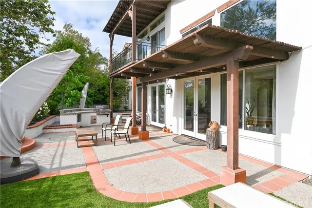 a view of a patio with table and chairs under an umbrella with a barbeque