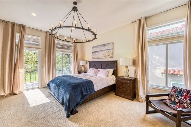 a bedroom with a bed a chandelier and a large window