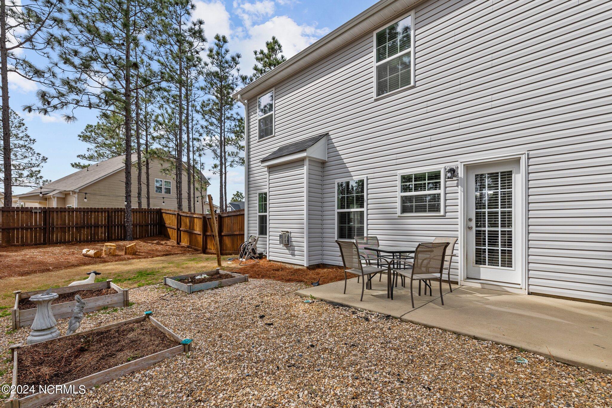 4055 Irwin Drive Aberdeen, NC 28315 - Photo 30 of 32 Patio Area with Cafe Lighting and Adjacent Garden Beds