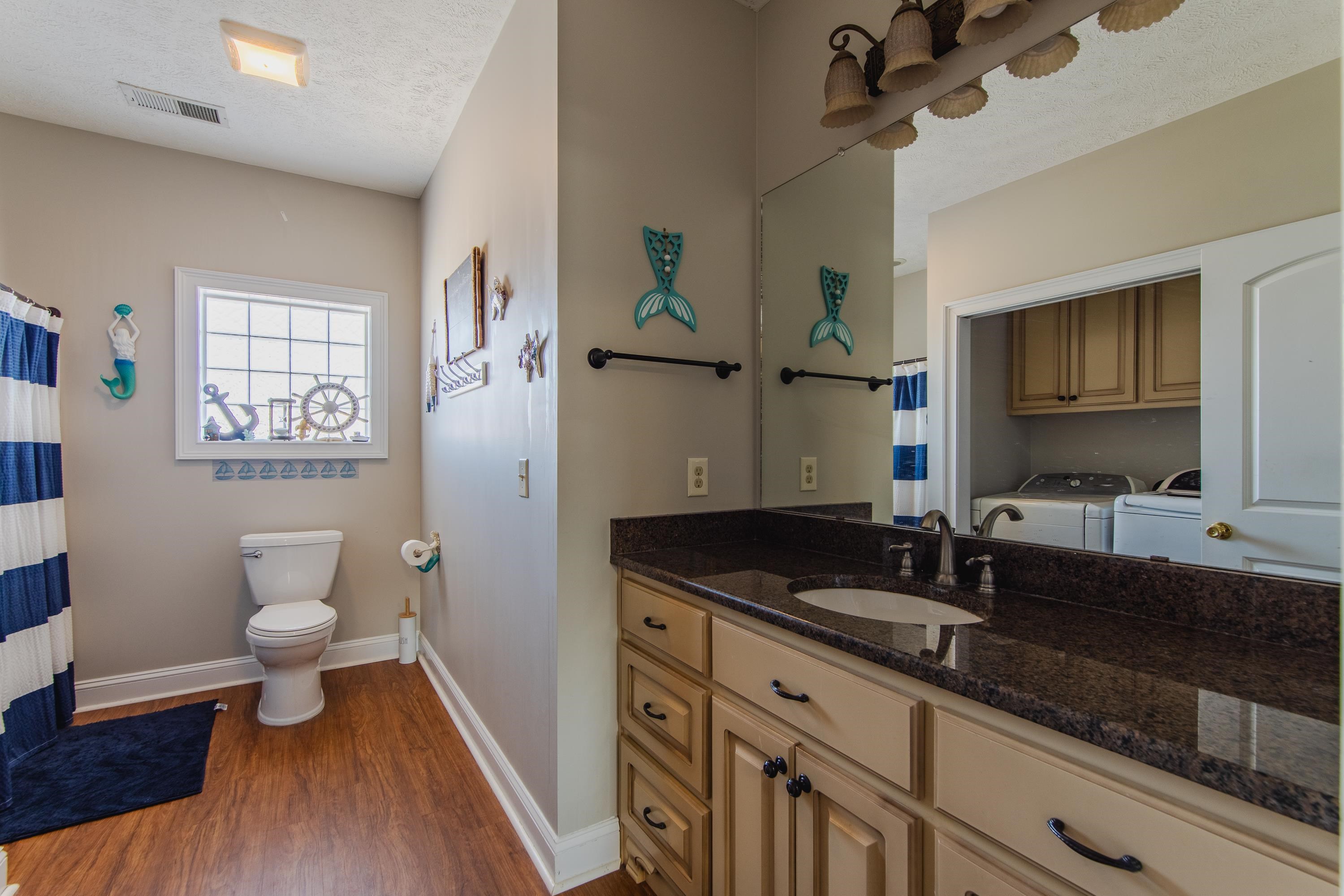 1111 Leaning Trees Lane Adamsville, TN 38310 - Photo 14 of 36 Bathroom featuring vanity, hardwood / wood-style flooring, toilet, independent washer and dryer, and a textured ceiling
