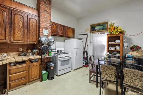 a kitchen with stainless steel appliances a refrigerator a stove a sink a dining table and chairs with wooden floor