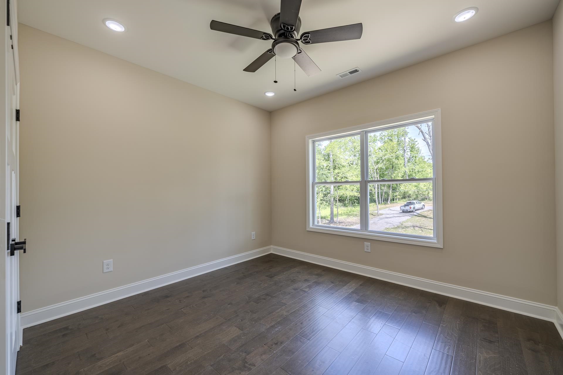 50 Fox Trot Road Adamsville, TN 38310 - Photo 20 of 40 an empty room with wooden floor ceiling fan and windows