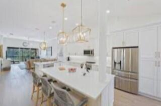 a kitchen with kitchen island a dining table chairs stainless steel appliances and cabinets