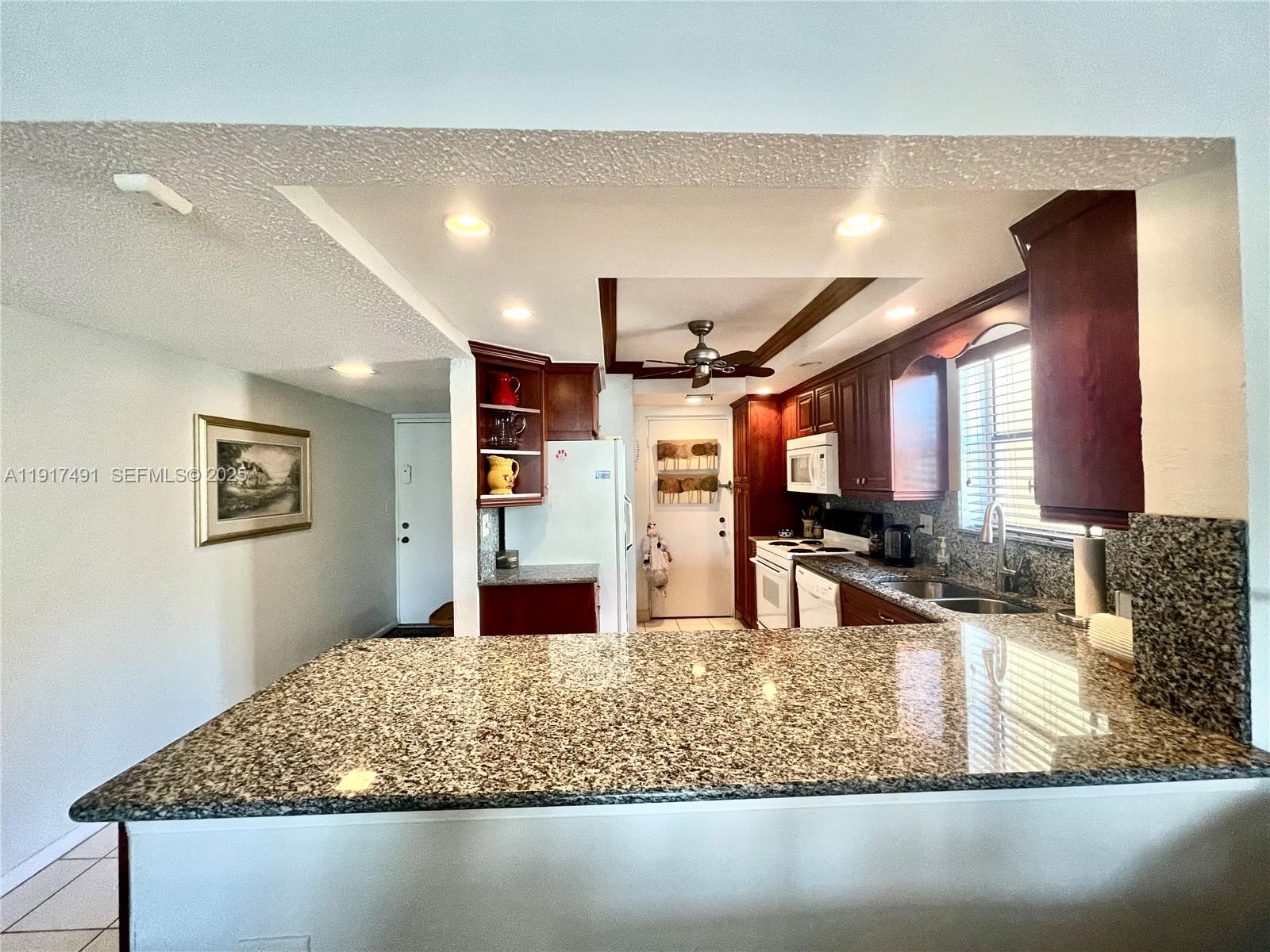 2309 South Cypress Bend Drive, Unit 311 Pompano Beach, FL 33069 - Photo 11 of 51 a kitchen with stainless steel appliances kitchen island granite countertop a sink and a granite counter top