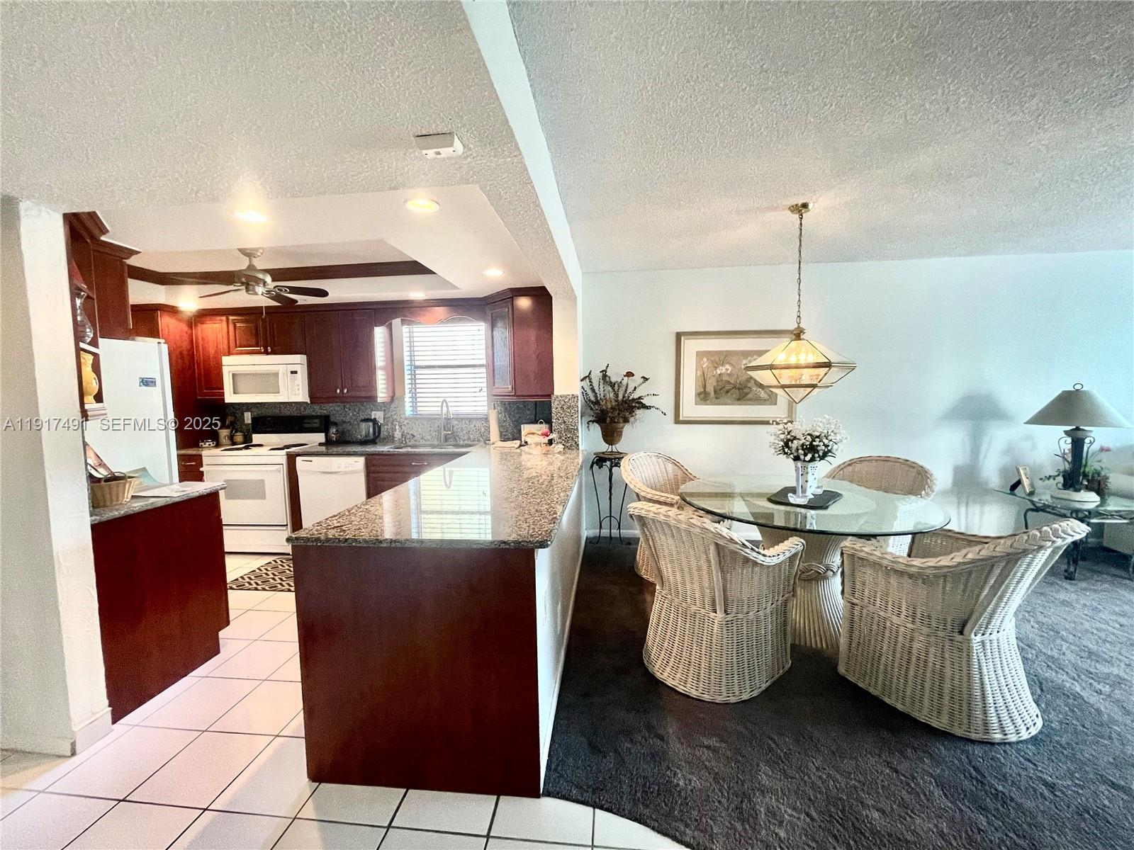2309 South Cypress Bend Drive, Unit 311 Pompano Beach, FL 33069 - Photo 12 of 51 a living room with stainless steel appliances kitchen island granite countertop a table chairs and a wooden floors