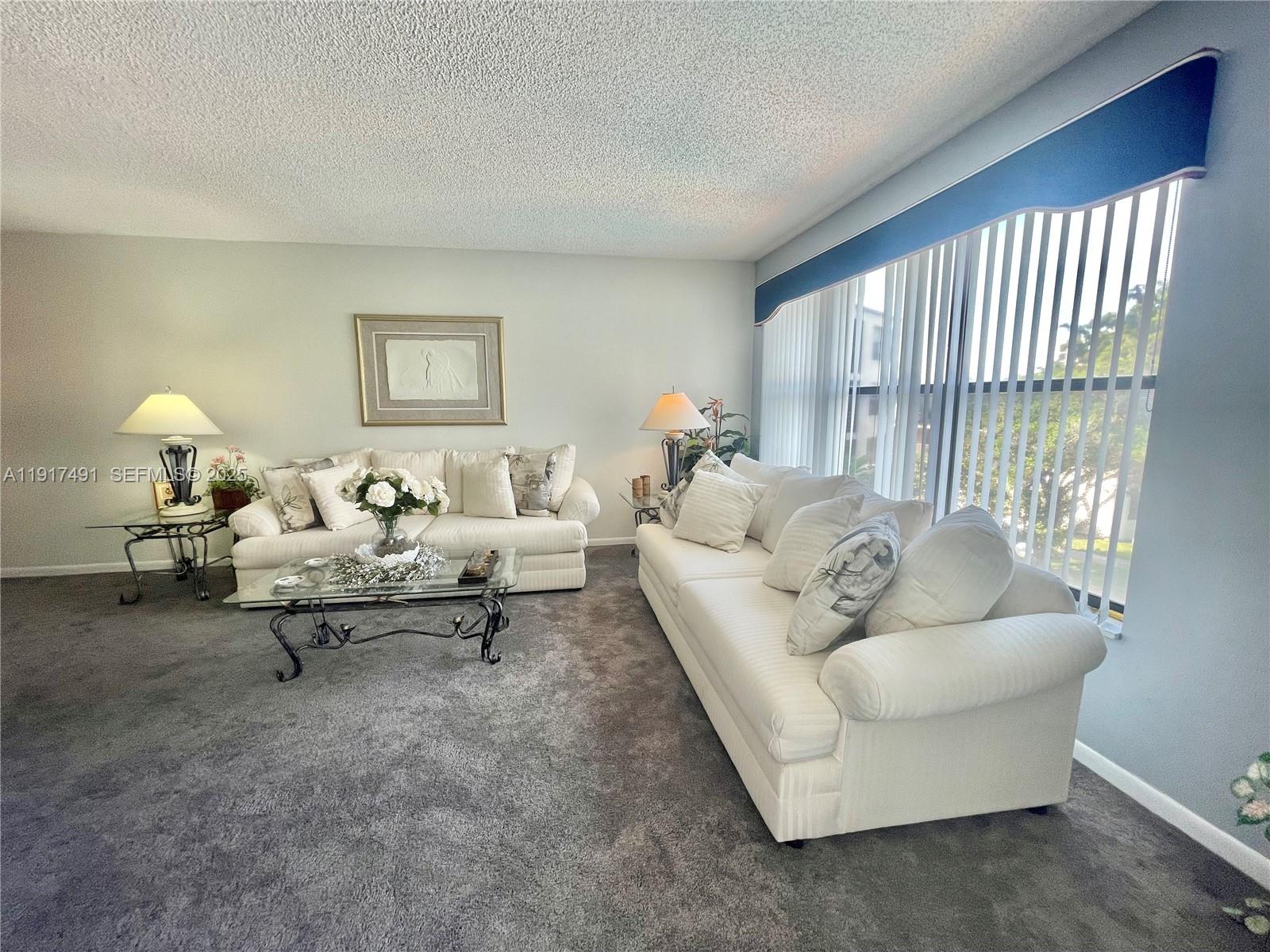 2309 South Cypress Bend Drive, Unit 311 Pompano Beach, FL 33069 - Photo 17 of 51 a living room with furniture and a lamp