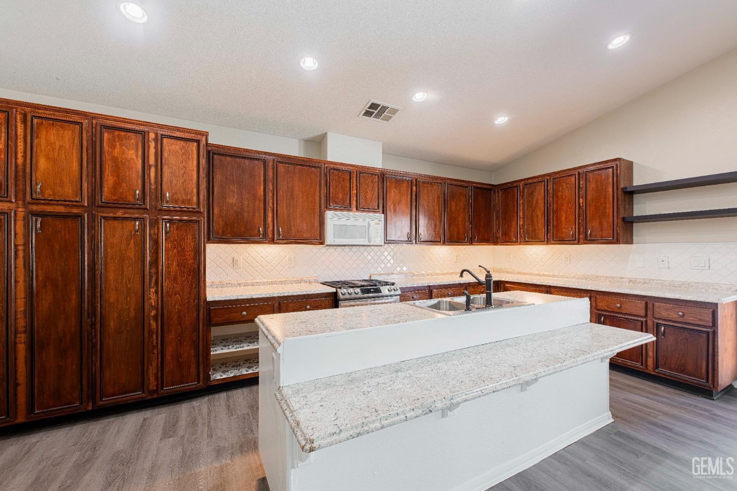 Undisclosed Address Bakersfield, CA 93312 - Photo 16 of 44 a kitchen with stainless steel appliances granite countertop a sink a stove and a wooden cabinets