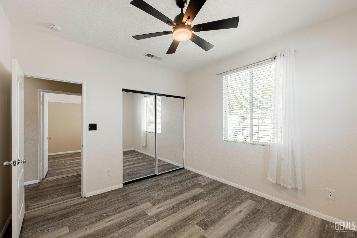 Undisclosed Address Bakersfield, CA 93312 - Photo 27 of 44 a view of an empty room with wooden floor and a ceiling fan