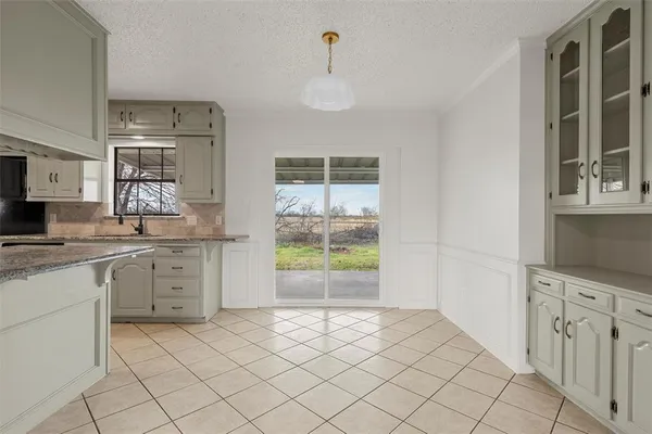 a kitchen with white cabinets and window