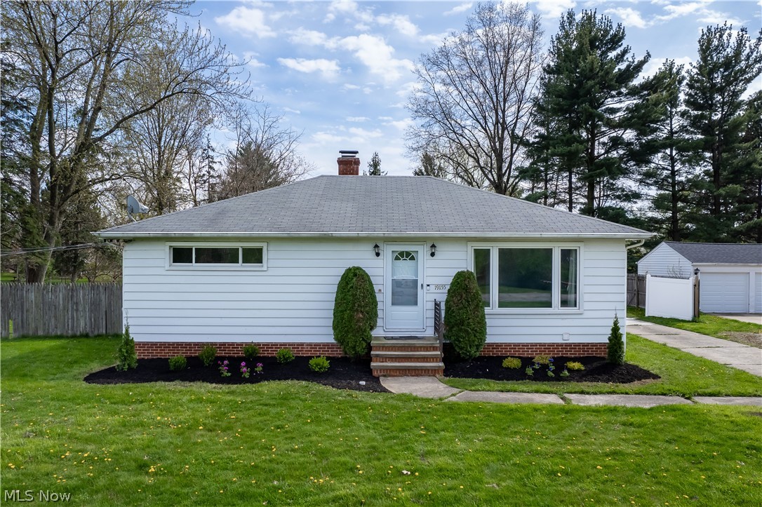Ranch-style home featuring a garage, an outdoor structure, and a front lawn