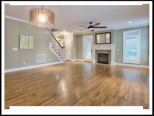 a view of an empty room with wooden floor fireplace and a window