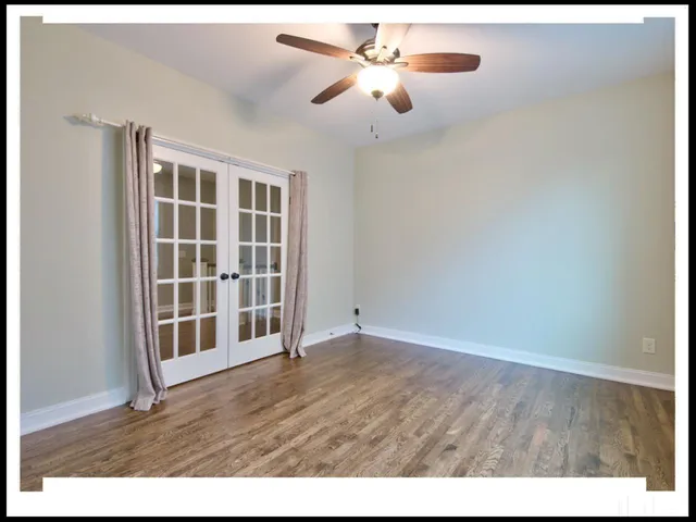 a view of an empty room with chandelier fan