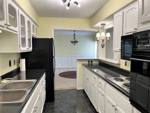 a kitchen with granite countertop white cabinets and black appliances