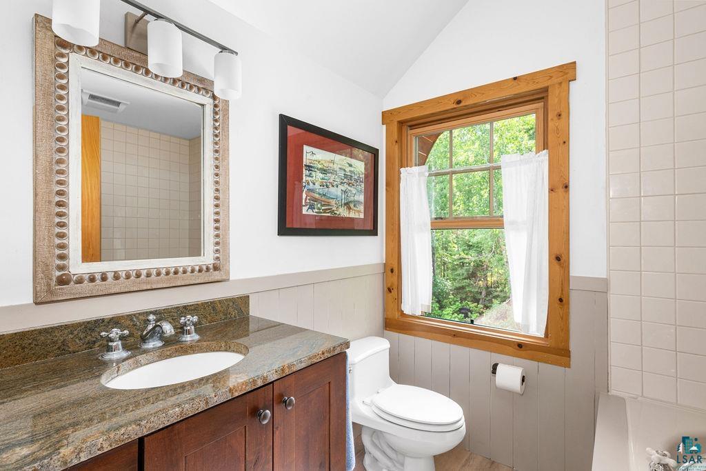 4015 East Van Road Duluth, MN 55803 - Photo 18 of 31 Bathroom featuring lofted ceiling, vanity, and wainscoting