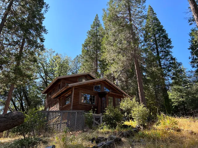 a view of a small house with a small yard and covered trees