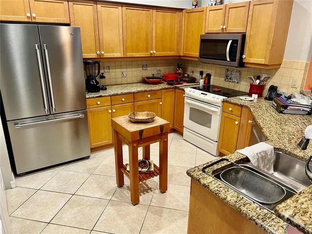 a kitchen with stainless steel appliances granite countertop a sink stove microwave and refrigerator