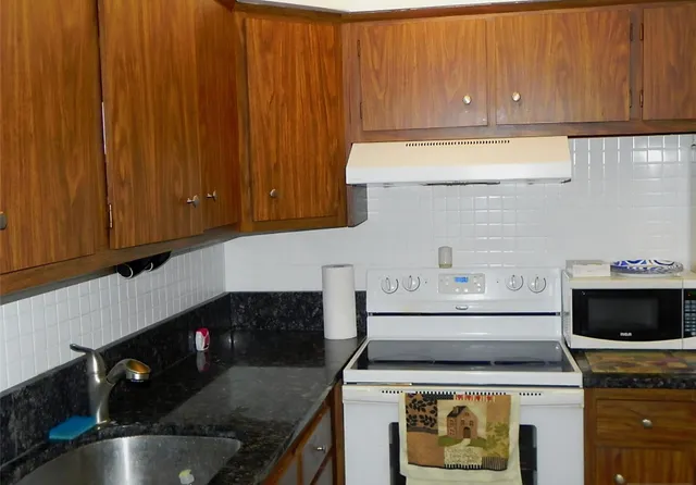 a kitchen with a stove a microwave a sink and cabinets