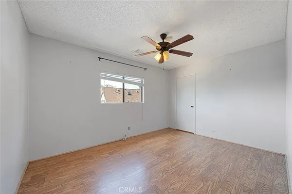 a view of a big room with wooden floor and chandelier fan