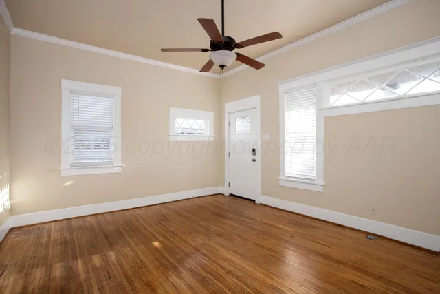 a view of an empty room with wooden floor and a window