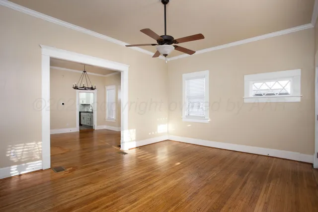 a view of an empty room with window and wooden floor