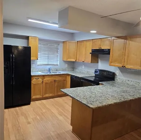 a kitchen with granite countertop a sink a counter top space and cabinets