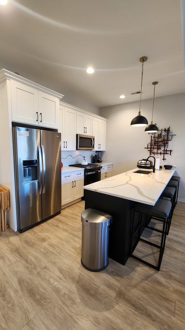 4902 South St Lawrence Avenue, Unit 2 Chicago, IL 60615 - Photo 5 of 11 a kitchen with stainless steel appliances granite countertop a refrigerator a sink a stove a dining table and chairs