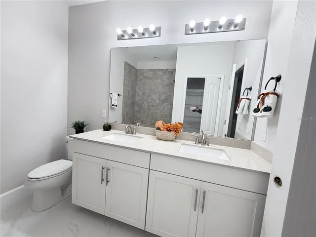 a bathroom with a double vanity sink and a toilet