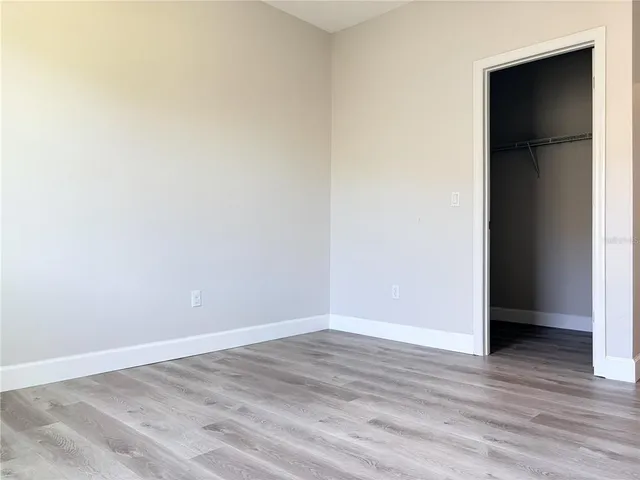 a view of an empty room with wooden floor and closet