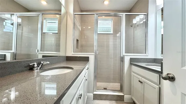 a bathroom with a granite countertop sink mirror and shower