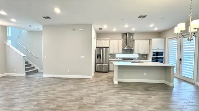 a kitchen with stainless steel appliances granite countertop a refrigerator a sink dishwasher a stove and white countertops with wooden floor