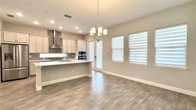 a view of an empty room with kitchen and window