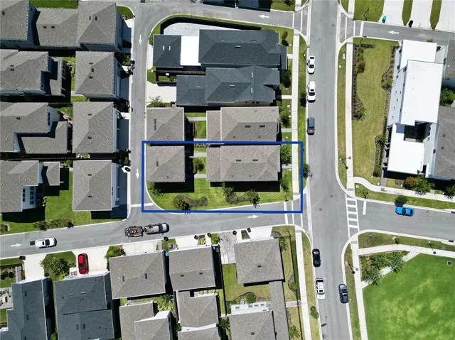 an aerial view of residential houses with outdoor space and parking
