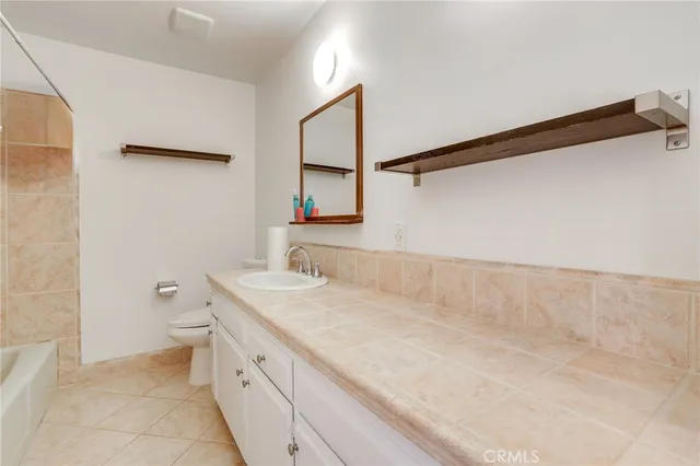 a bathroom with a granite countertop sink a toilet and a mirror
