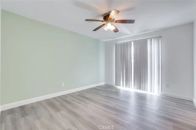 an empty room with wooden floor chandelier fan and windows