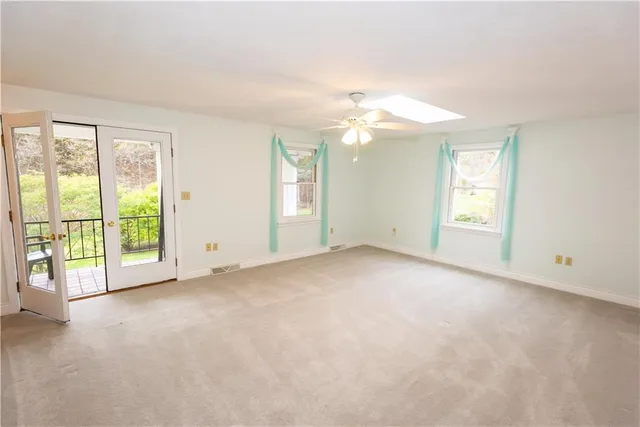 an empty room with windows and chandelier fan
