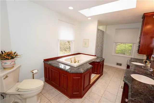a spacious bathroom with a granite countertop toilet sink and mirror