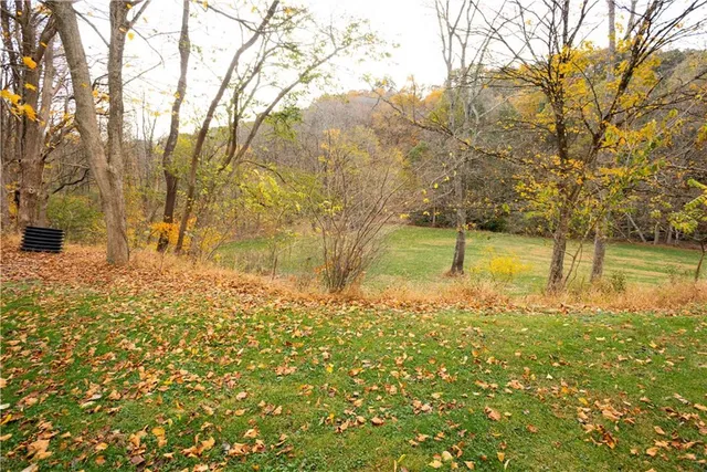 a view of a white house with a big yard and large trees