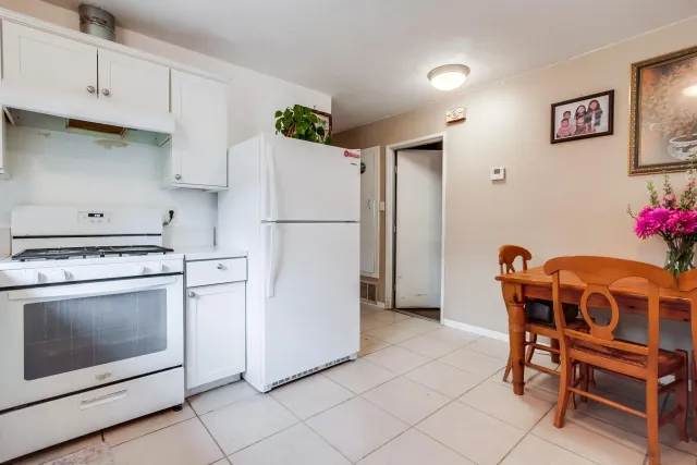 a white kitchen with a stove a refrigerator and a table