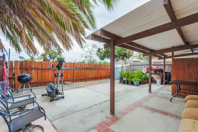a view of a patio with a table and chairs under an umbrella with a small garden