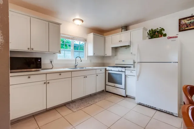 a kitchen with white cabinets and white appliances