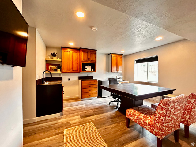 1373 South Raintree Lane Santaquin, UT 84655 - Photo 18 of 29 Wood-finish flooring throughout a versatile room featuring a built-in wet bar with a black cabinet and faucet, natural wood cabinetry, recessed lighting, and a window with a black roller shade