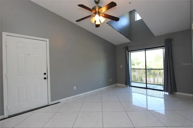 a view of an empty room and window and chandelier fan