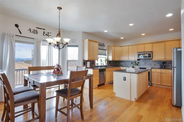 a kitchen with stainless steel appliances kitchen island granite countertop a dining table chairs and white cabinets