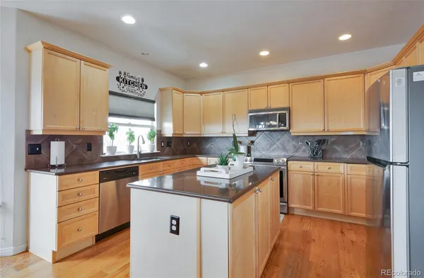 a kitchen with stainless steel appliances granite countertop a stove a sink and a refrigerator
