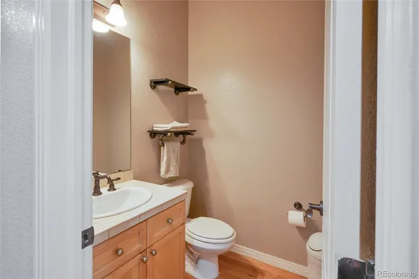 a bathroom with a granite countertop toilet a sink and a mirror