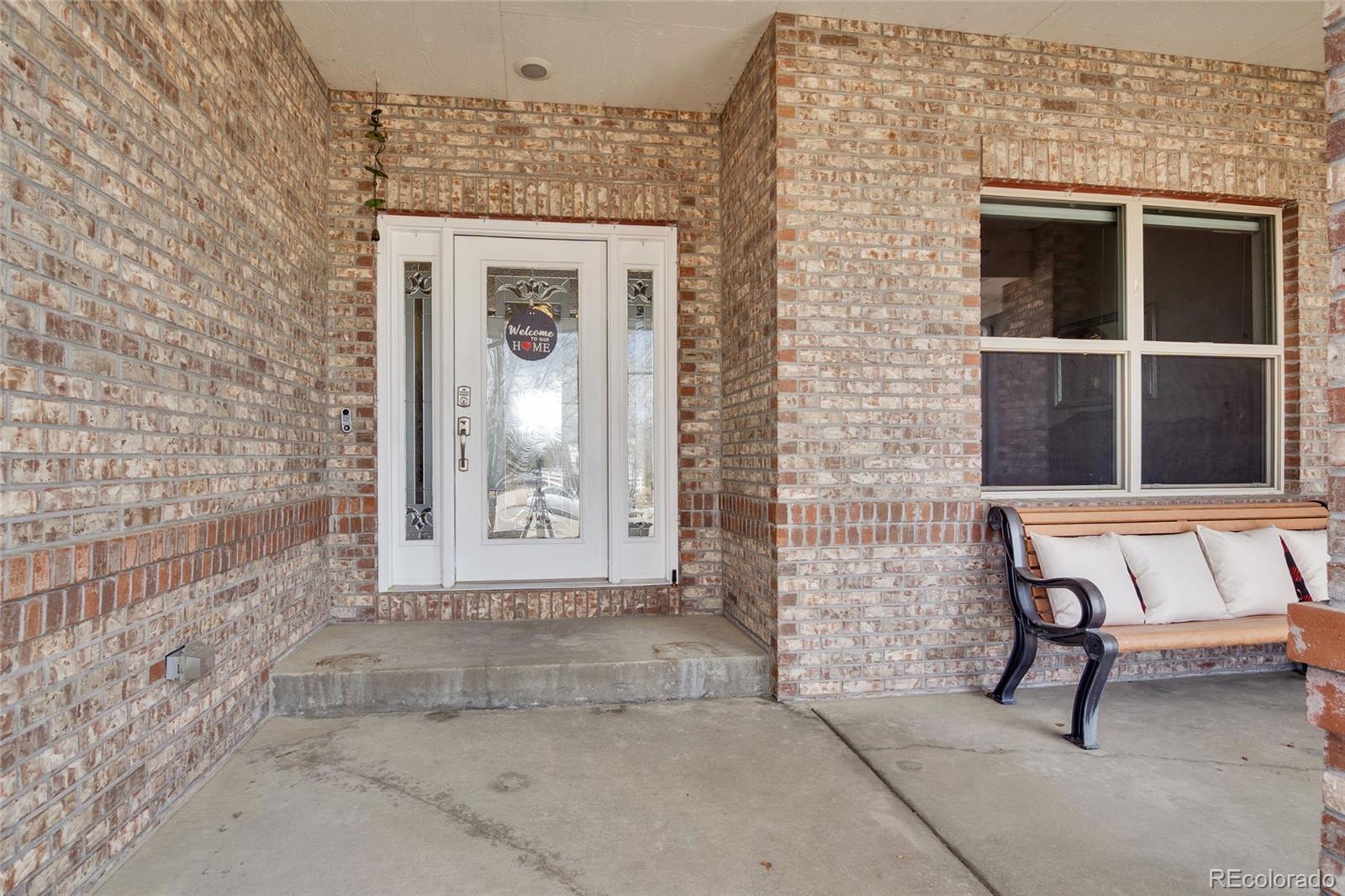 271 Corvette Circle Fort Lupton, CO 80621 - Photo 5 of 39 a view of a brick house with a bench and a window